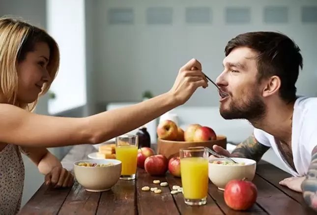 A woman feeds a man with nuts to increase potency